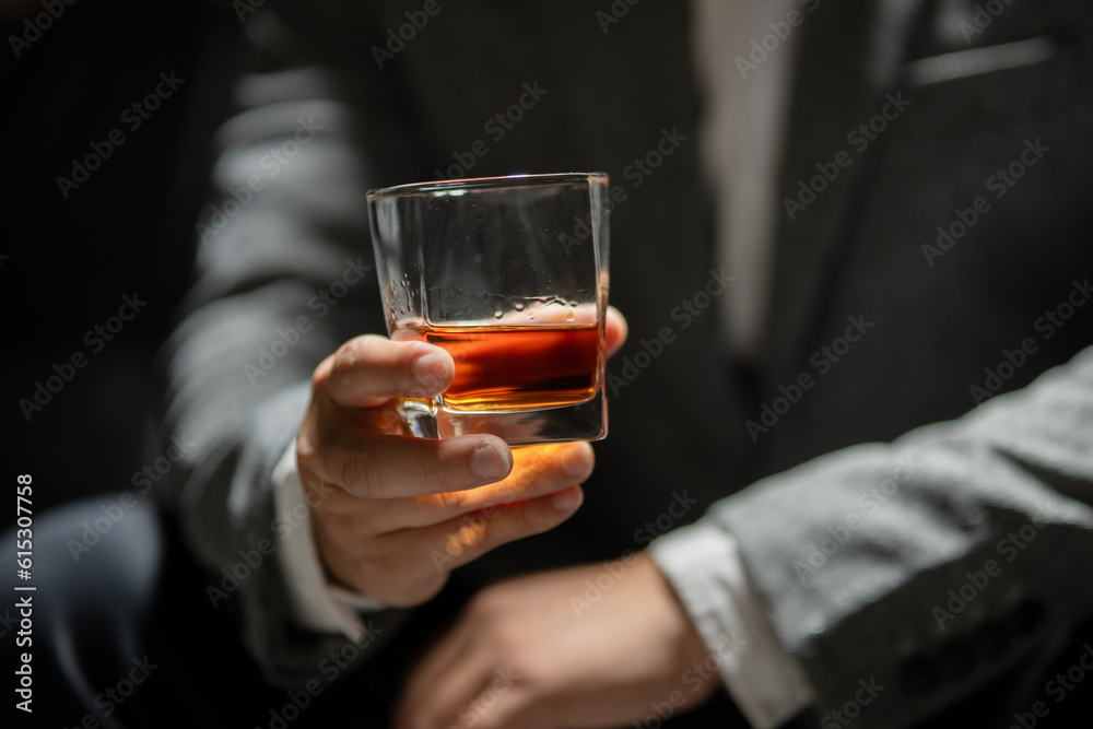 Businessman sitting Holding a Glass of Whiskey Drink Whiskey in the liquor store room Businessman sitting Holding a Glass of Whiskey Drink Whiskey in the liquor store room