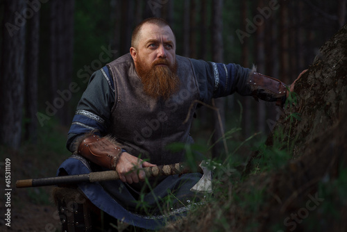 Lurking medieval red-haired viking warrior with beard with an ax in forest © Fotokvadrat