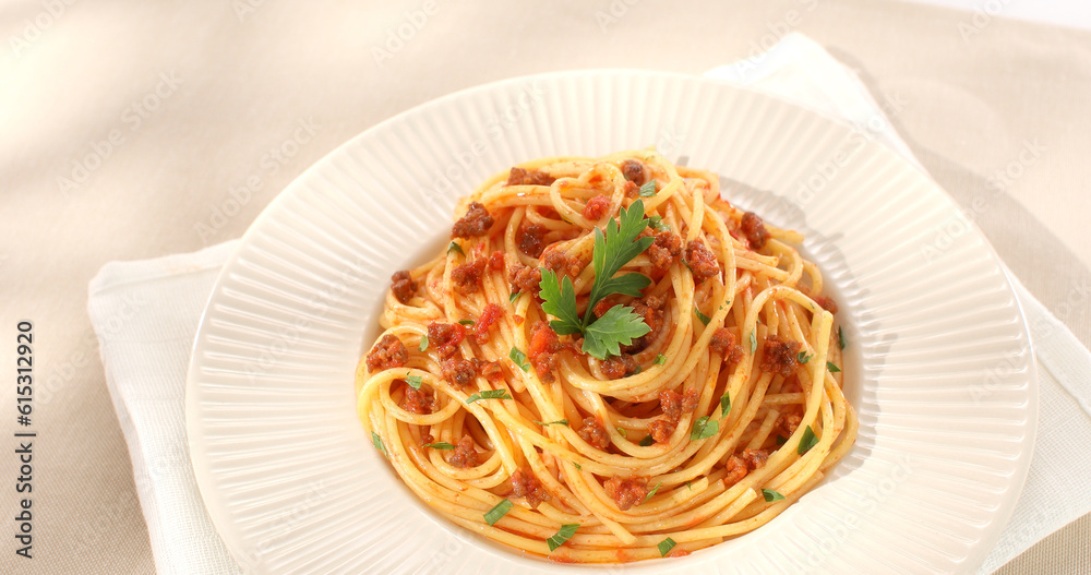 spaghetti bolognese on a white plate. classic italian pasta with meat tomato sauce on a light background. dish of mediterranean cuisine. food on the table on a sunny day. yellow noodles, minced meat.
