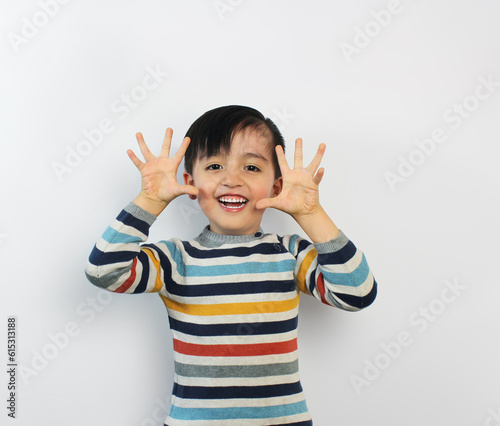 smiling boy showing his face, palms facing forward, wearing a colorful striped sweater