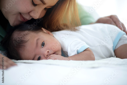 Cute newborn baby lying prone in bed while mother sings him lullaby