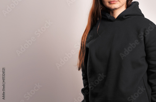 Woman Showcasing a Black Hoodie for Logo Branding. Streetwear clothing mock-up. Logo on shirt template copy space.