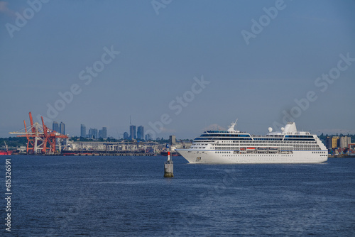 Sail away departure of luxury cruiseship cruise ship liner Regatta from port of Vancouver BC, Canada for Alaska cruising on sunny day with city skyline and container harbor Stanley Park