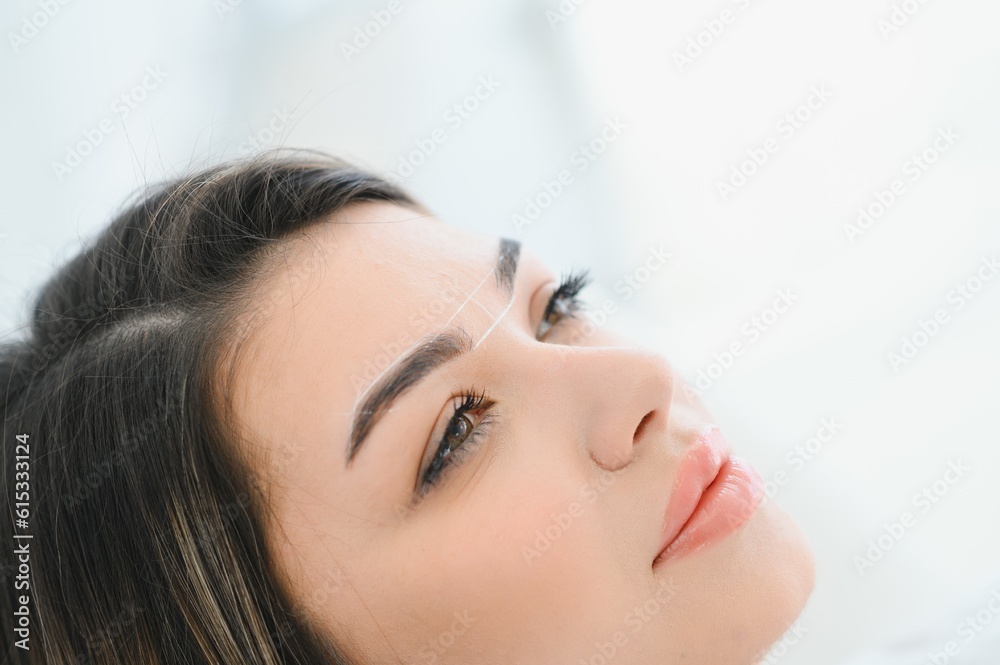 Young woman during professional eyebrow mapping procedure. Young woman during professional eyebrow mapping procedure.