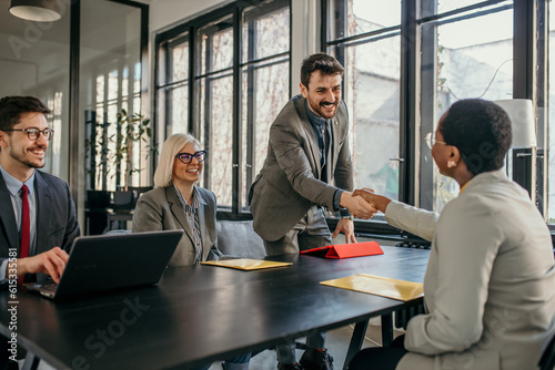 Smiling businessman shaking hand with new client in a modern office photo