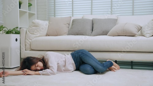 Young asian woman sick feeling dizzy and faint falling down lose consciousness on floor front of sofa in living room at home. Healthcare and medical concept photo