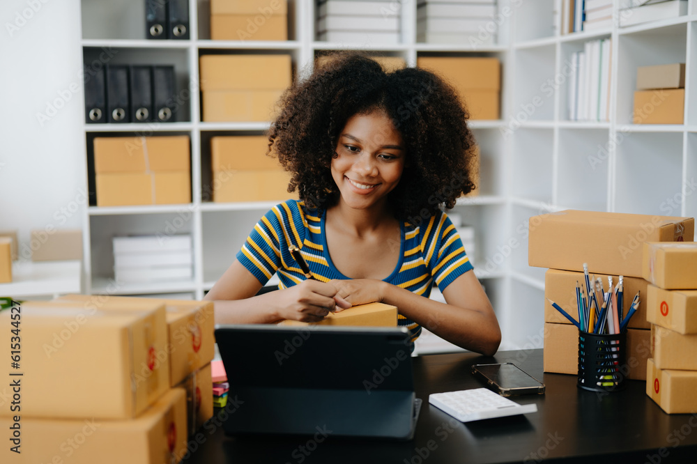 Small business entrepreneur SME freelance African woman working at home office, BOX,tablet and laptop online, marketing, packaging, delivery, e-commerce concept Small business entrepreneur SME freelance African woman working at home office, BOX,tablet and laptop online, marketing, packaging, delivery, e-commerce concept