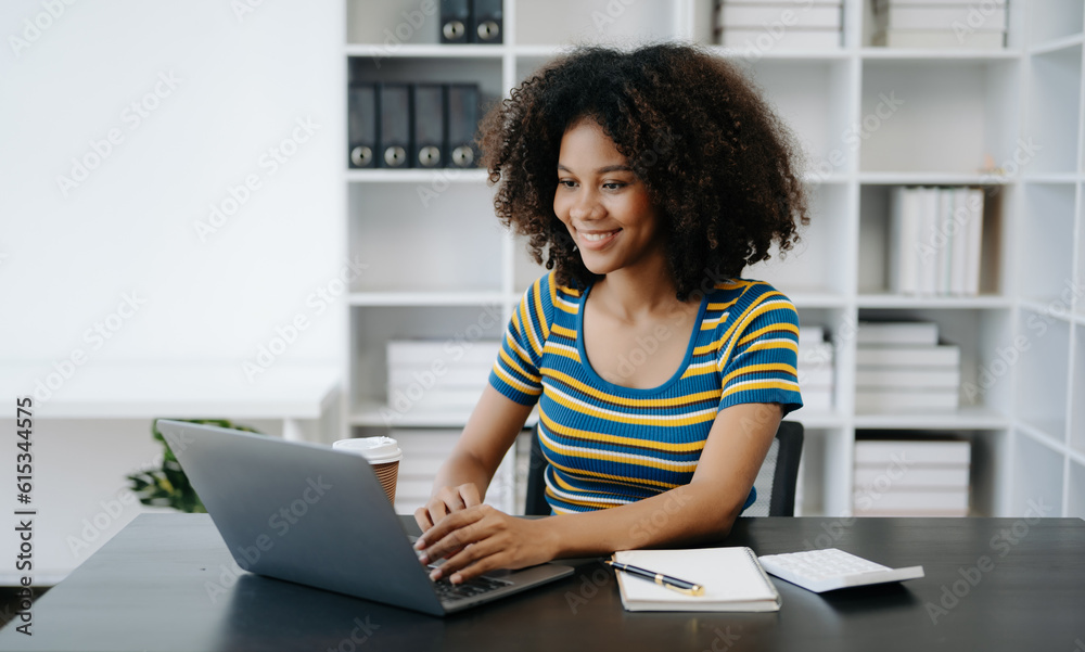 Beautiful African woman using laptop and tablet while sitting at her working place. Concentrated at work in home office Beautiful African woman using laptop and tablet while sitting at her working place. Concentrated at work in home office