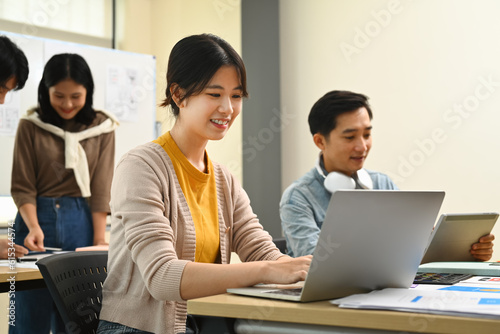 Young female ux designer working on mobile application software design project with colleagues in creative office
