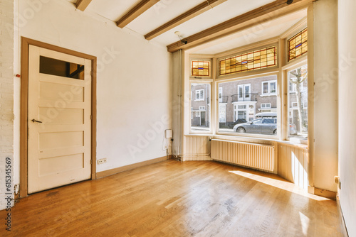 an empty living room with wood flooring and white brick walls in the background is a large window that looks out onto the street