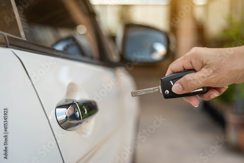 Female hand pushing remote key of white car