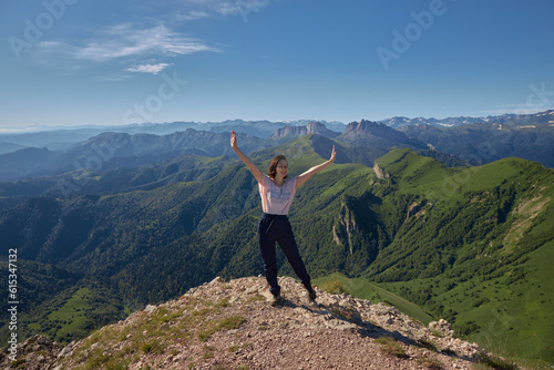 woman on top of mountain, raising arms. young woman with her arms up on top of a mountain