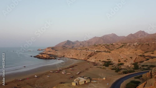 Aerial drone tilt up shot over Kund Malir Beach alongside a road beside Ormara Hingol national park with mountain range in the background in Balochistan. photo