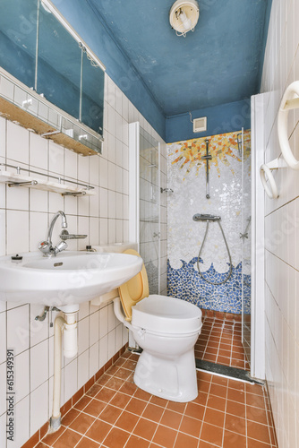 a bathroom with blue and white tiles on the walls, sink, mirror, and toilet in an empty room