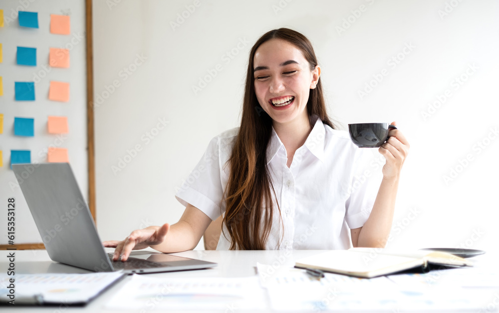 Asian businesswoman smiling happily with a new morning holding a cup of coffee lightly sipping coffee professional woman in size working in the office Asian businesswoman smiling happily with a new morning holding a cup of coffee lightly sipping coffee professional woman in size working in the office