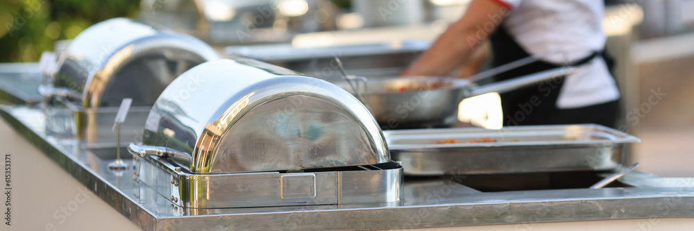 Row of chafing dishes closeup. Cooked meat vegetables and garnish are on large baking sheet. Food concept for restaurants and cafes Row of chafing dishes closeup. Cooked meat vegetables and garnish are on large baking sheet. Food concept for restaurants and cafes