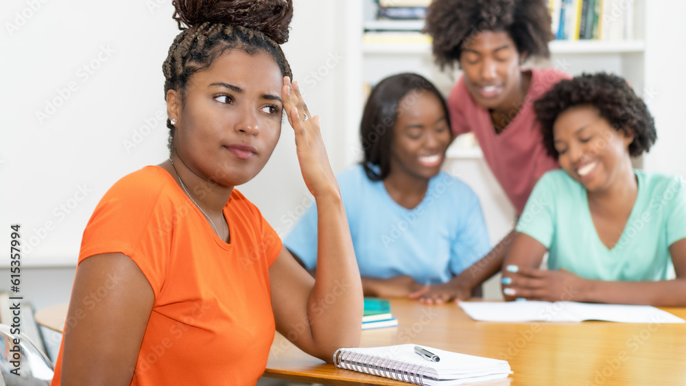 Black female student with problems at desk with group of learning african american students Black female student with problems at desk with group of learning african american students