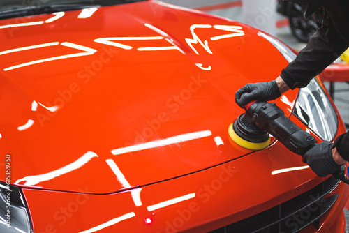 Canvas-taulu Professional car detailing expert using machine polish on a bonnet of a vivid red sports car
