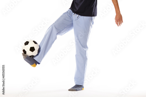 Fototapeta Naklejka Na Ścianę i Meble -  Young man in pajama playing football. Legs. Night wear