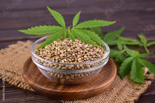 Healthy hemp seeds in a wooden bowl and hemp leaves. Close-up
