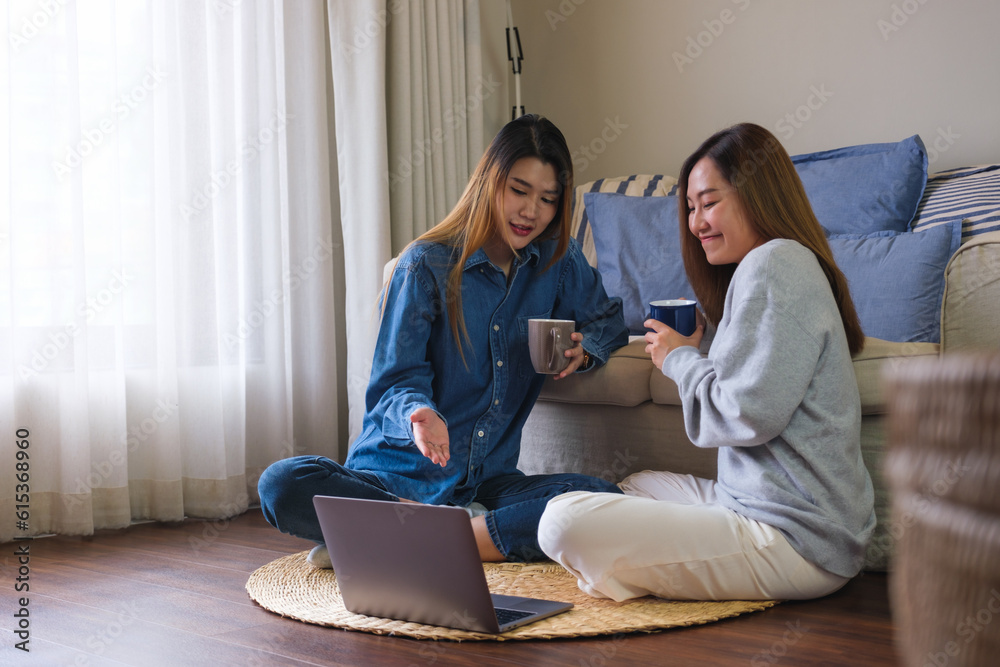 Portrait image of two women drinking coffee while watching on laptop computer together at home Portrait image of two women drinking coffee while watching on laptop computer together at home