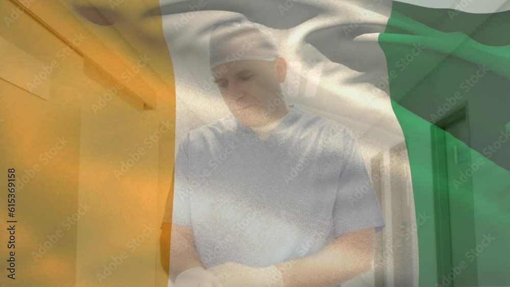 Animation of flag of ivory coast, caucasian surgeon adjusting gloves and rushing to operation room