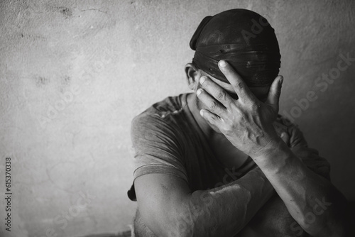 A drug addicted homeless man sitting alone and depressed in an abandoned house feeling anxious and lonely.
