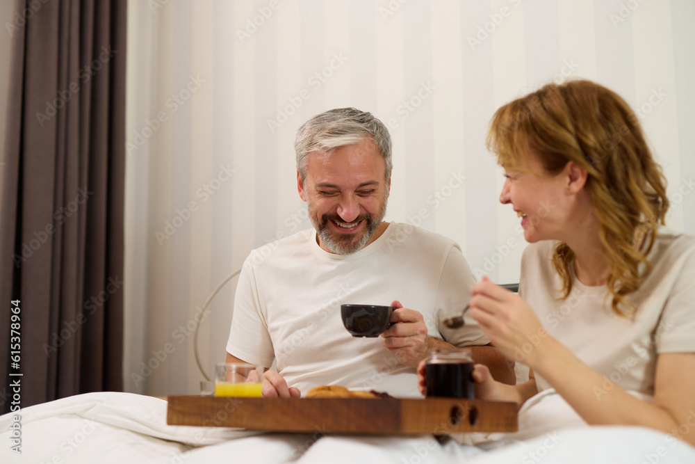 Mature couple enjoying coffee and breakfast at home in bed Mature couple enjoying coffee and breakfast at home in bed