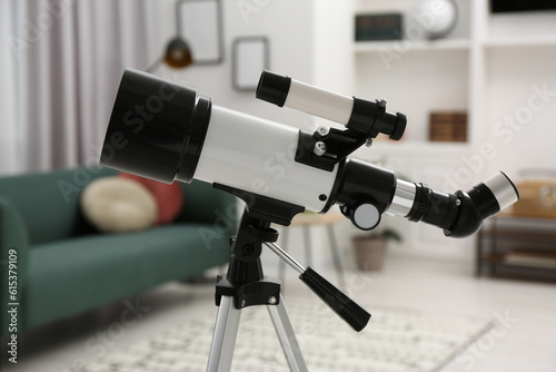 Tripod with modern telescope in living room