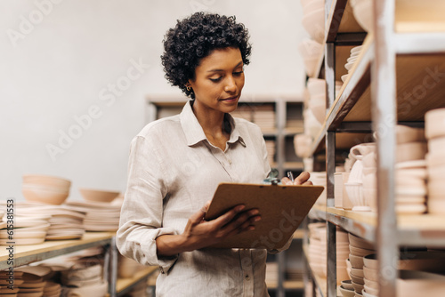 Принти на полотні Female ceramic shop owner taking inventory in her store