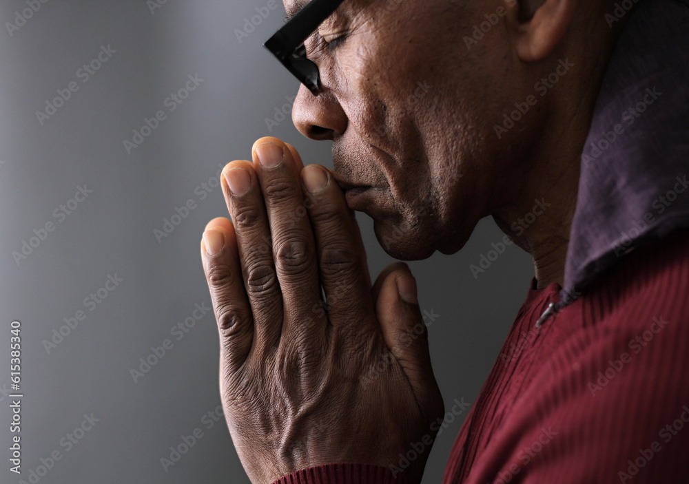man praying to god with hands together Caribbean man praying stock photo	