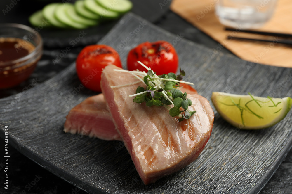 Pieces of delicious tuna with microgreens, lime and tomatoes on table, closeup Pieces of delicious tuna with microgreens, lime and tomatoes on table, closeup