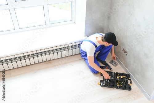 Construction worker electrician assembles an electrical outlet in an apartment