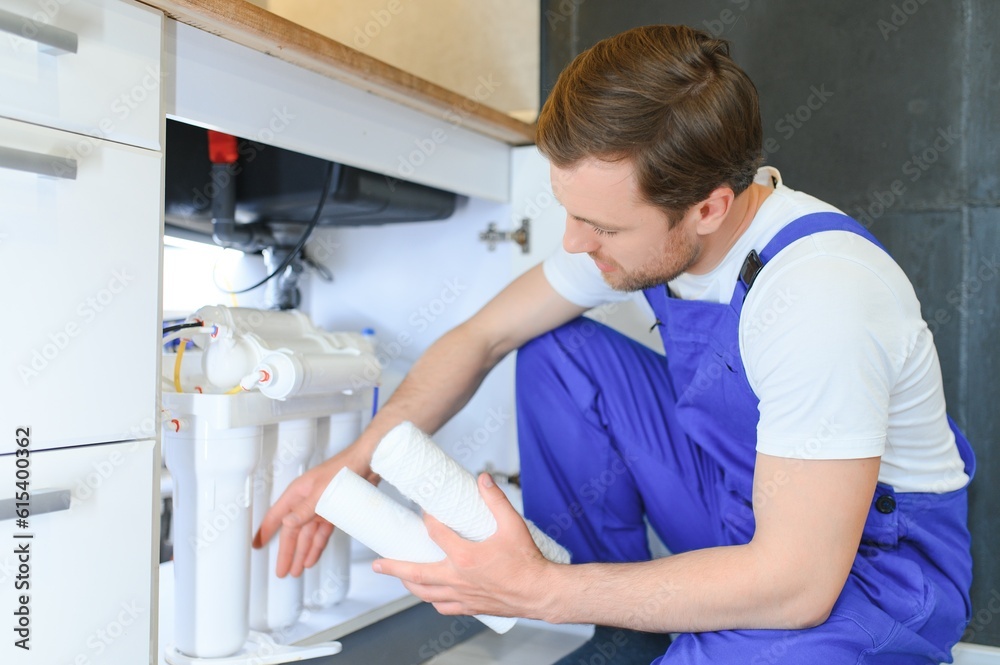 Young plumber or technician installing or repairing system of water filtration Young plumber or technician installing or repairing system of water filtration