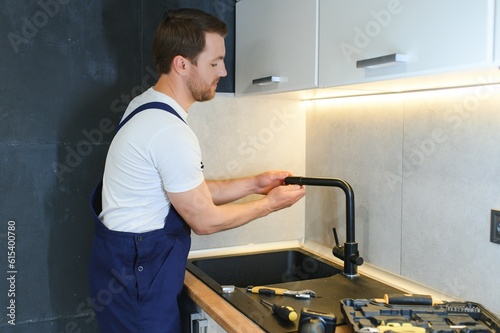 Professional plumber fixing water tap in kitchen
