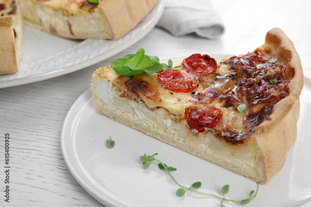 Piece of delicious homemade quiche with prosciutto and tomatoes on white wooden table, closeup