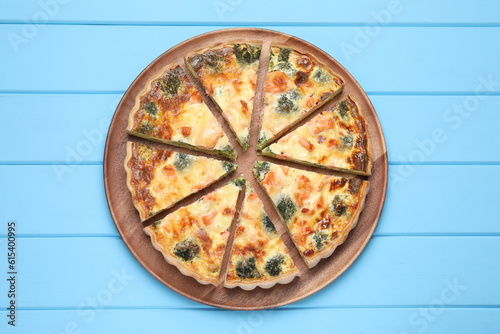 Delicious homemade quiche with salmon and broccoli on light blue wooden table, top view