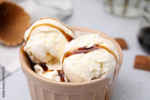 Scoops of ice cream with caramel sauce and candies on light grey table, closeup