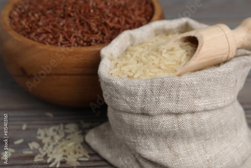 Bag and bowl with different sorts of rice on wooden table, closeup