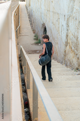 Young fashionable gay man with a bag goes down some stairs © Cristian Blázquez