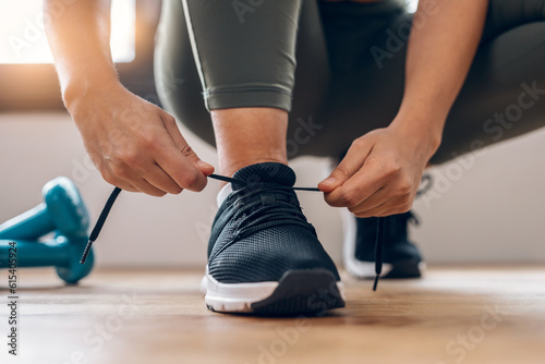 Athletic woman tying her sneakers at home.