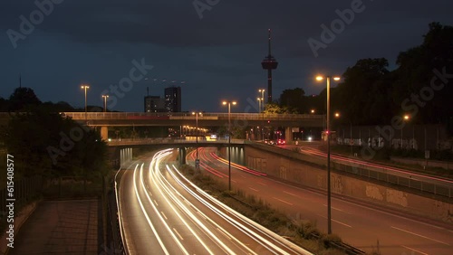 Traffic Flow and Cologne Skyline. Witness bustling cars with light strokes on a highway, a prominent TV tower, moving clouds, and Cologne's panoramic skyline in the evening. Energy and dynamism. 003 photo