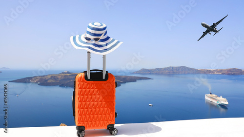 The travel concept with Orange luggage and hat as landscape view of Oia town in Santorini island in Greece