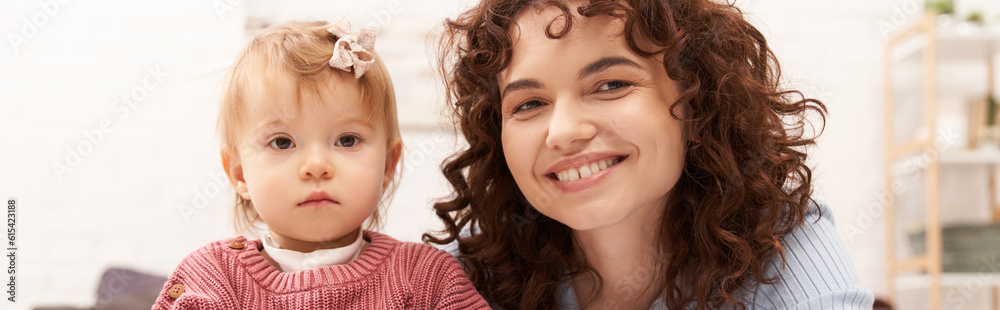 portrait of happy woman and child, curly working mother hugging baby girl, balanced lifestyle, bonding, family time, modern parenting, engaging with kid, loving motherhood, banner portrait of happy woman and child, curly working mother hugging baby girl, balanced lifestyle, bonding, family time, modern parenting, engaging with kid, loving motherhood, banner