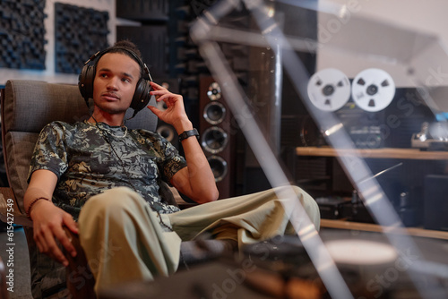 Portrait of young man listening to vinyl records at home and enjoying sound quality