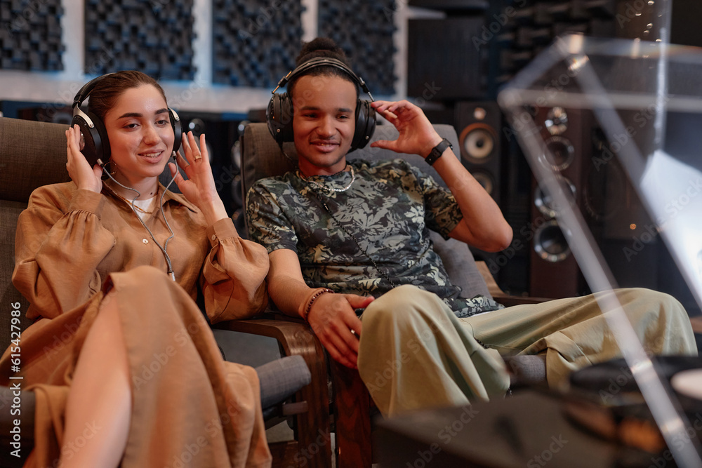 Portrait of young couple listening to vinyl records at home and enjoying sound quality