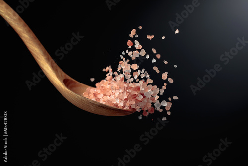 Pink Himalayan salt is poured with a wooden spoon.