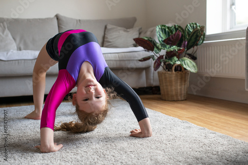 Slika na platnu Pretty young girl in gymnastics leotard sportswear doing fitness exercises at ho