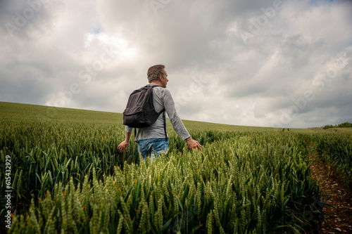 Man with a backpack walking through a field of wheat, getting away from it all.