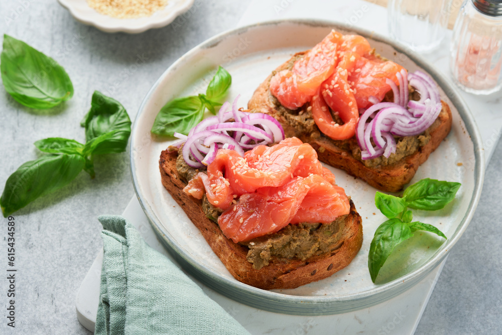 Sandwiches with salted salmon, avocado guacamole, red onions and basil. Smorrebrod. Set of danish open sandwiches. Healthy food, breakfast. Clean eating, dieting, vegan food concept. Top view. Sandwiches with salted salmon, avocado guacamole, red onions and basil. Smorrebrod. Set of danish open sandwiches. Healthy food, breakfast. Clean eating, dieting, vegan food concept. Top view.
